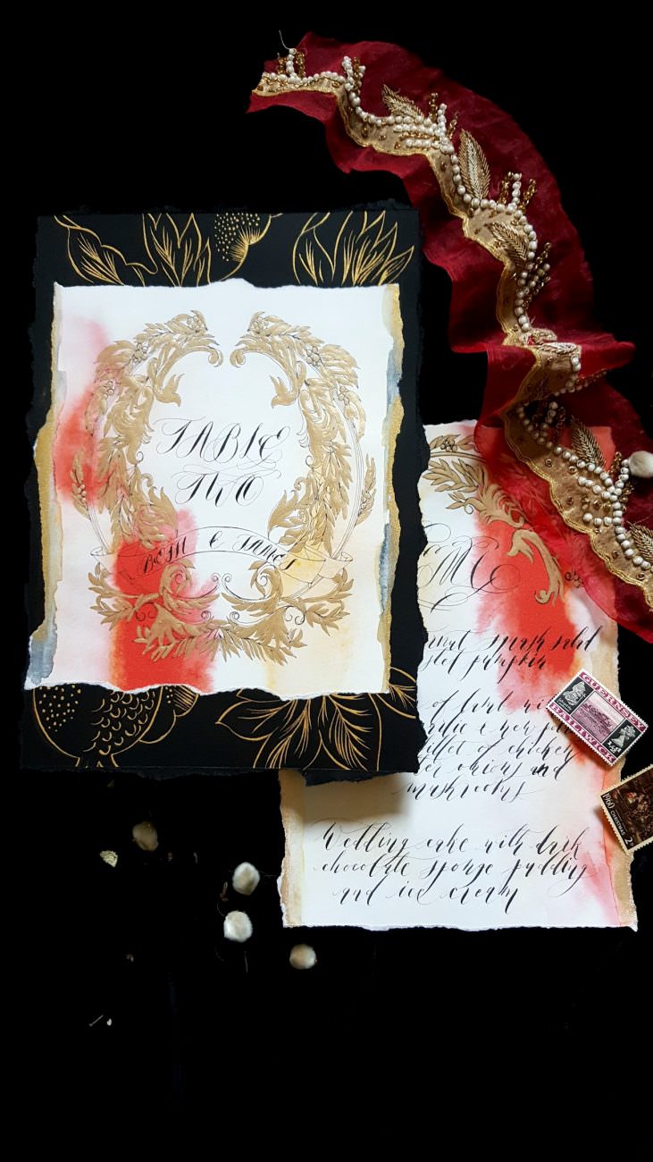 Hand Painted Wedding Stationery table number with orange watercolour and gold painted leaves on black background