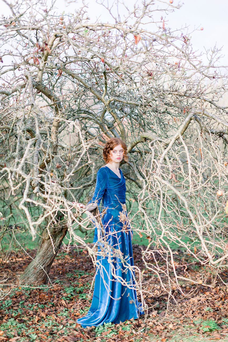 Baroque Wedding bride standing by a tree with blue velvet dress