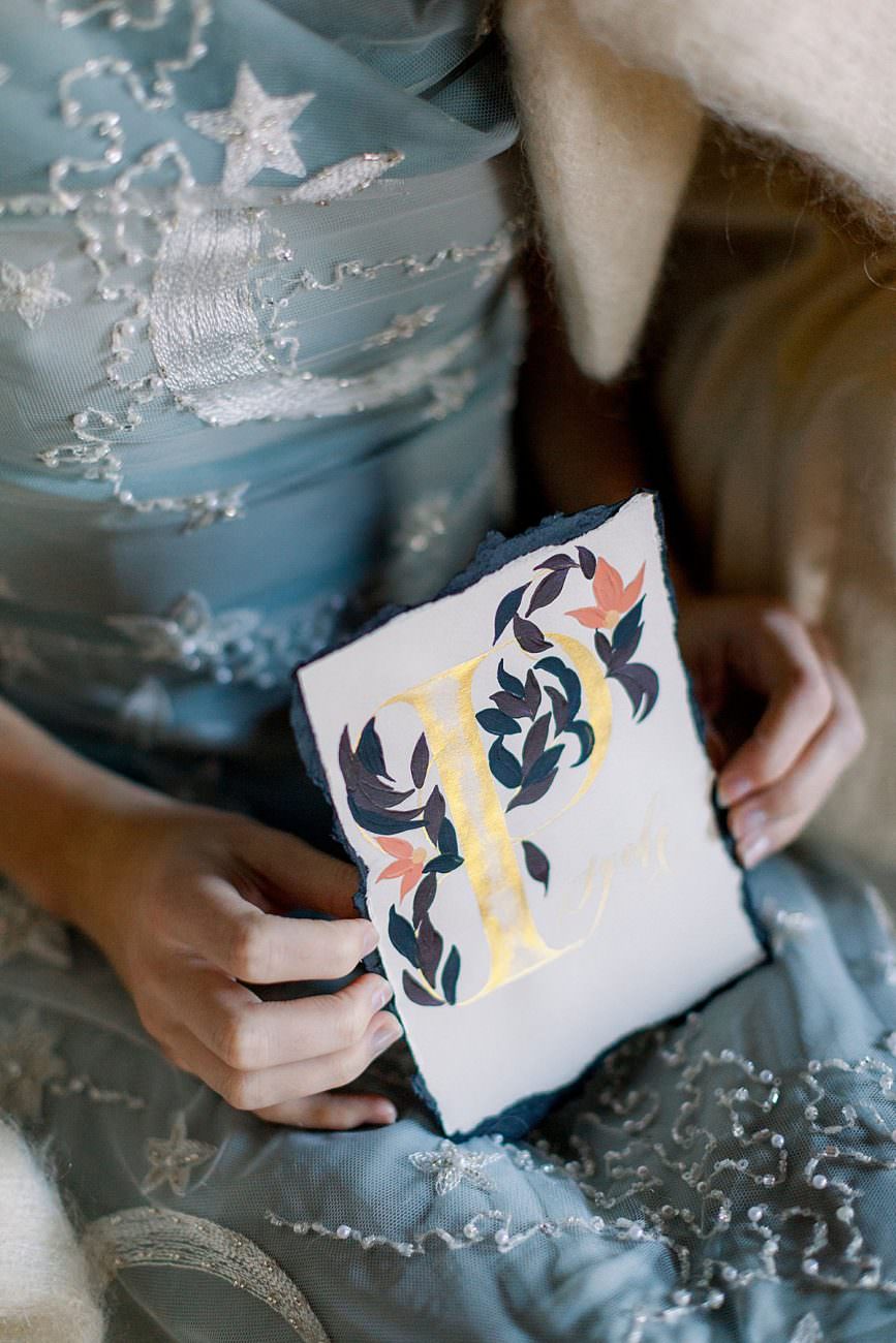 Baroque wedding inspiration showing bride in a pale blue dress holding antique place names