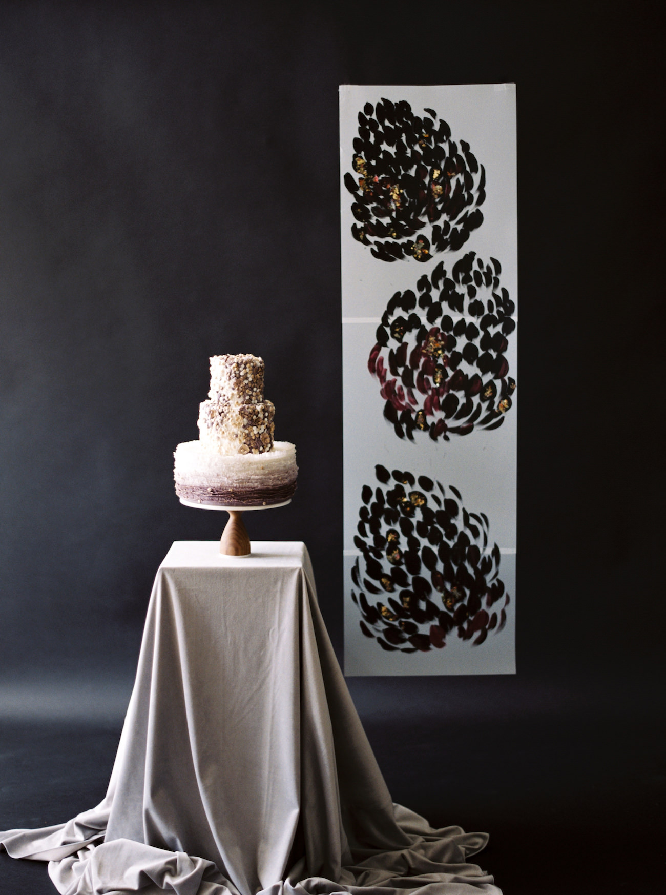 London Wedding Invitations cake displayed infront of a black backdrop with hand painted backdrop behind