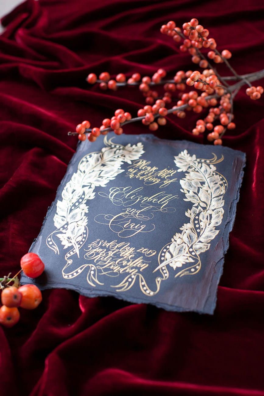 Black Wedding invite card close up details of gold painted crest