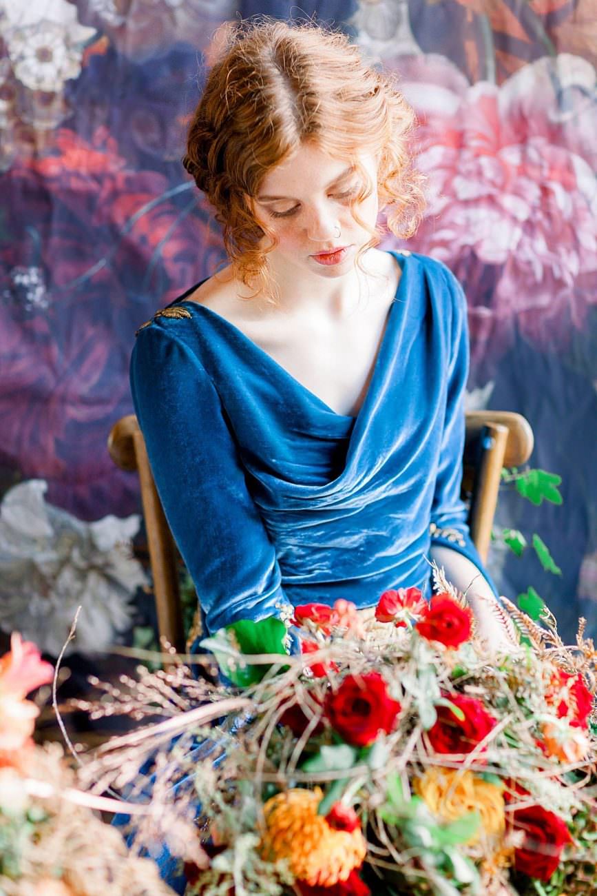 bride with red hair looking down onto large floral arrangement