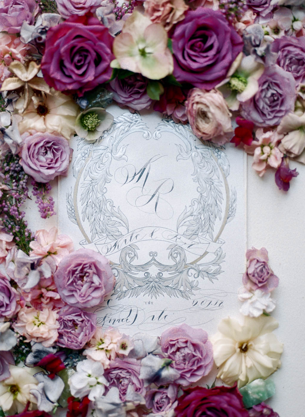 White and silver wedding crest with monogram design and styled with large pink roses