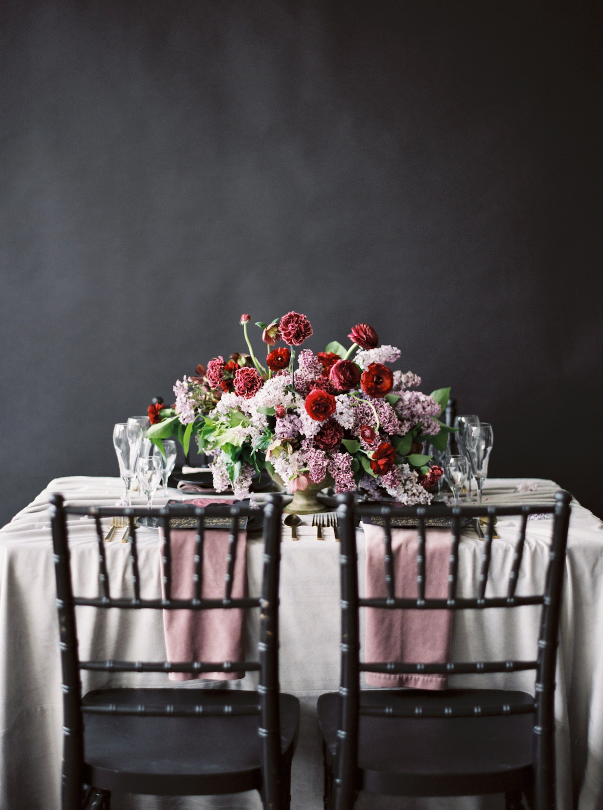 Moody wedding tablescape with black chairs andpale blush table cloth